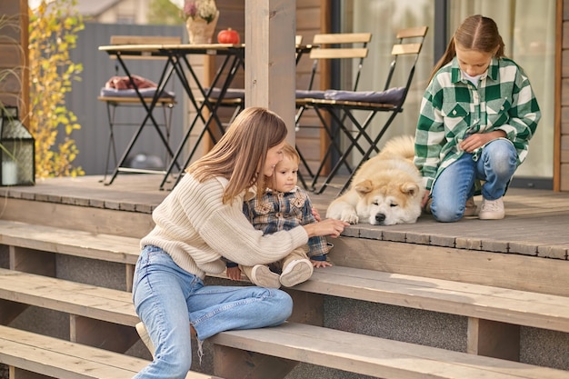 Femme avec enfant et fille regardant chien couché