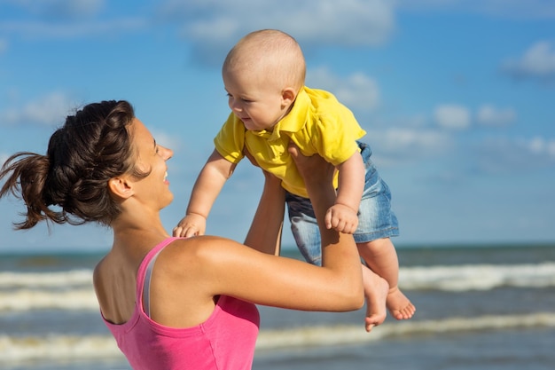 Une femme avec un enfant jouant sur la plage, maman avec bébé dans la nature