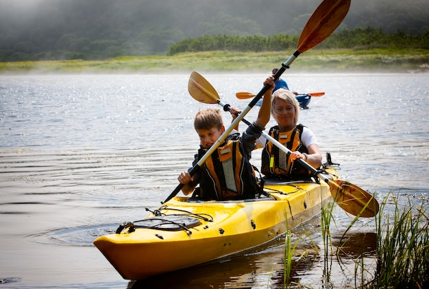 La femme avec un enfant sur le lac et monter en kayak