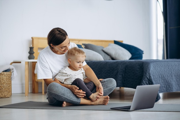 Femme avec enfant pratiquant le yoga à la maison