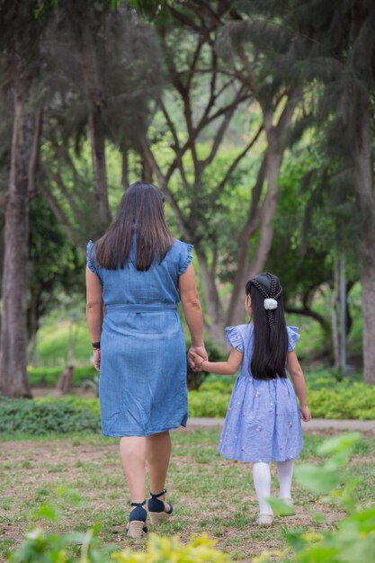 Photo une femme et un enfant se promènent dans un parc.