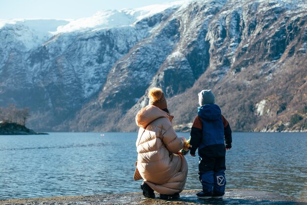 une femme avec un enfant se tient sur la rive du fjord et regarde les montagnes belle nature lan