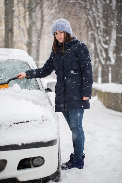 Femme enlevant la neige du pare-brise de voiture