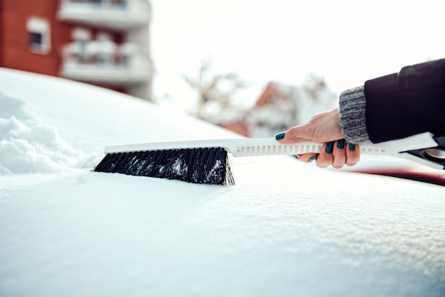 Photo femme enlevant la neige de la voiture