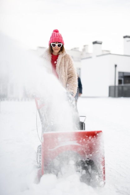 La femme enlève la neige du sentier avec une souffleuse à neige