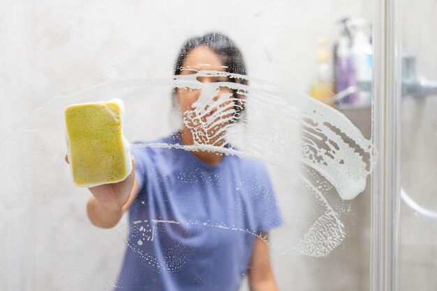 Femme enlève les taches d'eau dure et les dépôts dans la salle de bain