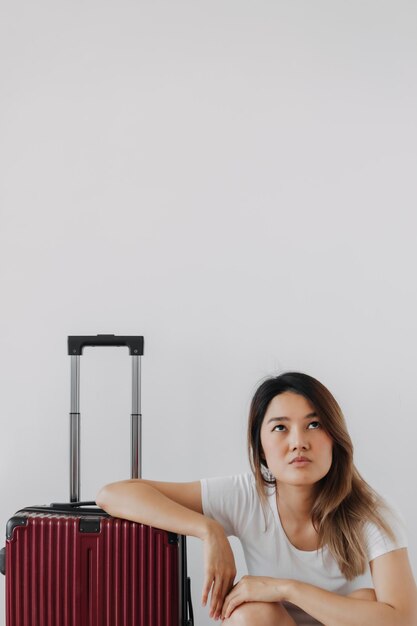 Une femme ennuyée et fatiguée dans ses vêtements de salon privés et ses bagages isolés sur blanc