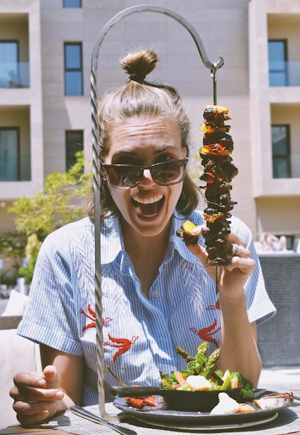 Photo une femme avec un énorme sourire à la bouche ouverte tenant de la viande au barbecue brésilienne avec son doigt