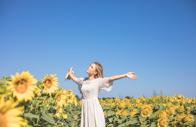 Femme ensoleillée de beauté sur le champ de tournesol jaune Concept de liberté et de bonheur Fille heureuse à l'extérieur