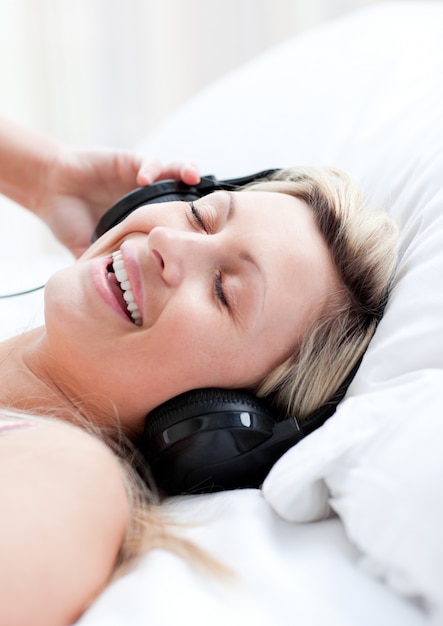 Femme enthousiaste avec un casque sur un lit