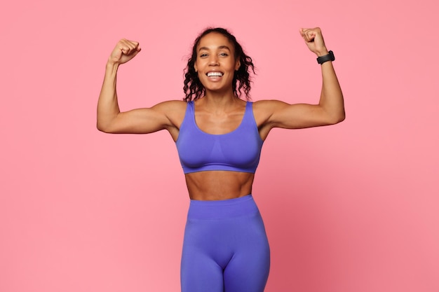 Photo une femme enthousiaste fléchissant ses muscles en tenue de sport en rose