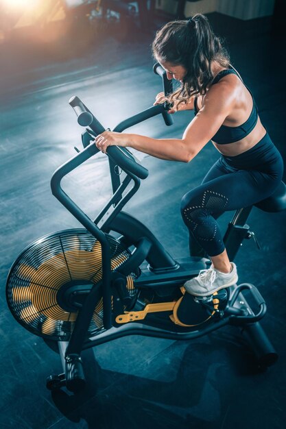 Photo femme d'entraînement cardio à l'aide d'un vélo pneumatique dans la salle de sport