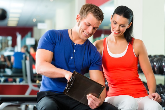 femme et entraîneur personnel dans une salle de sport avec des haltères