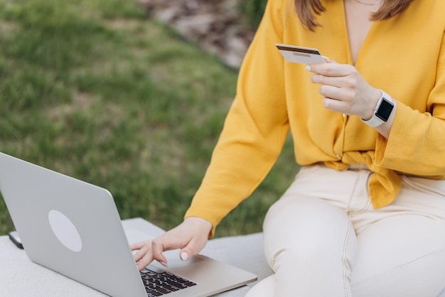 La femme entre dans le numéro de carte de crédit pour les achats en ligne à l'aide d'un téléphone portable assis dans la ville urbaine bu