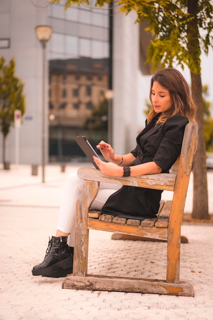 Femme entrepreneur à l'extérieur du bureau avec une tablette assise au repos