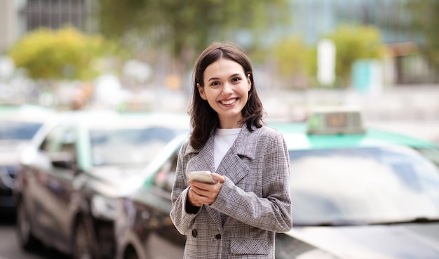 Femme d'entrepreneur heureuse utilisant un téléphone intelligent debout dans une zone urbaine