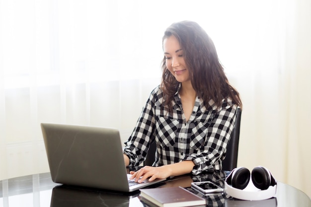 Femme entrepreneur avec une nouvelle entreprise en ligne travaillant à domicile dans la cuisine sur son ordinateur portable