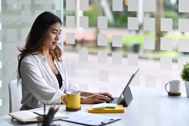 Femme entrepreneur séduisante travaillant avec une tablette informatique dans un lieu de travail moderne