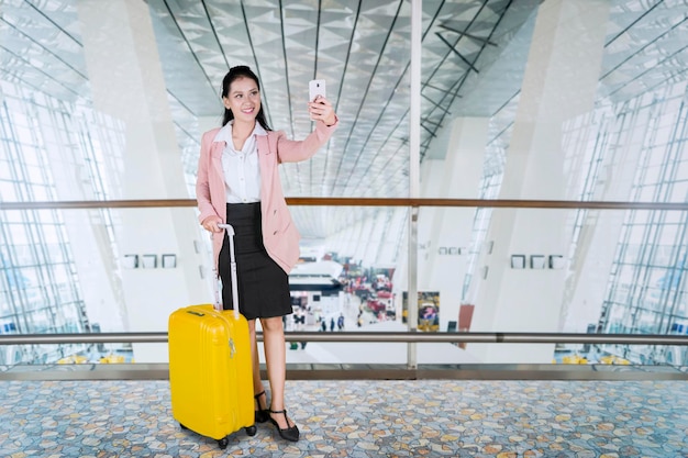 Une femme entrepreneure prenant un selfie à l'aéroport