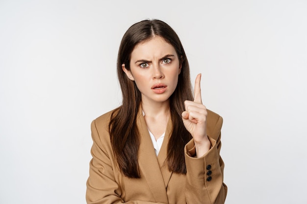 Femme d'entreprise en colère, patron secouant la désapprobation du doigt, gronder quelqu'un, interdire quelque chose, debout sur fond blanc.