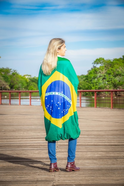 Femme enveloppée dans un drapeau brésilien portant un chapeau et un jean