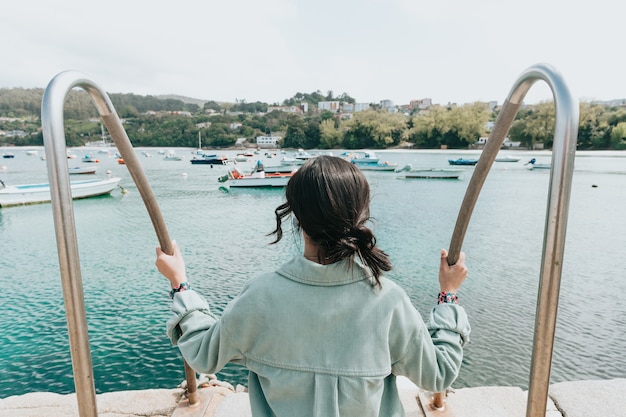 Femme à l'envers devant la mer avec beaucoup de bateaux pendant une journée ensoleillée