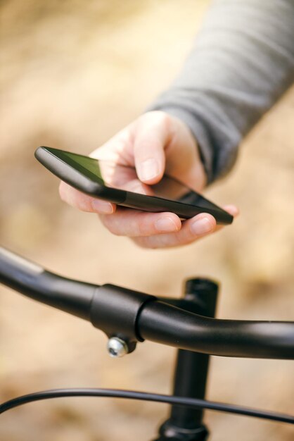 Une femme envoie des messages au téléphone en faisant du vélo.