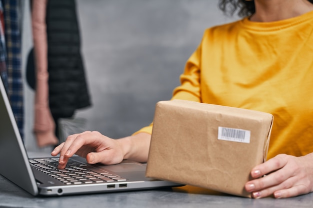 Femme envoyant un colis à l'aide de son ordinateur portable travaillant à domicile