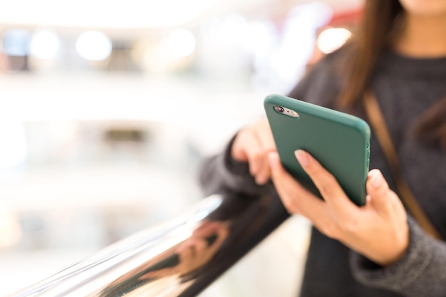 Femme envoyant des sms sur un téléphone portable dans un centre commercial