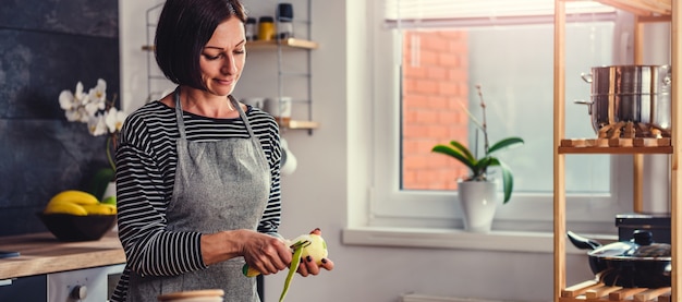 Femme éplucher des pommes dans la cuisine