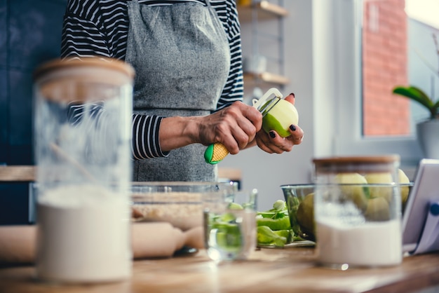 Femme éplucher des pommes dans la cuisine