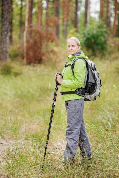 Femme avec équipement de randonnée marchant dans la forêt