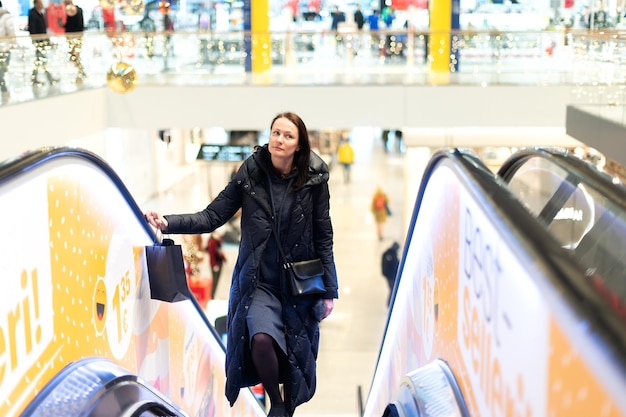 Femme sur l'escalator du centre commercial