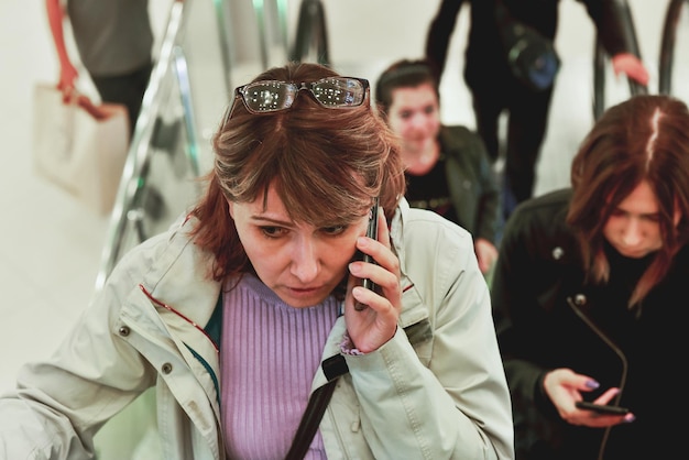 Une femme sur l'escalator parle au téléphone