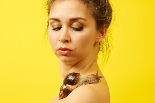 Une femme avec un escargot sur son corps sur fond jaune