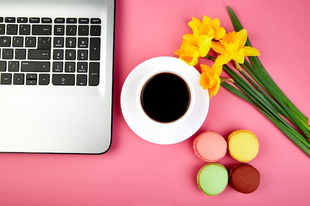 Femme ou espace de travail féminin avec carnet, café, macarons et fleurs