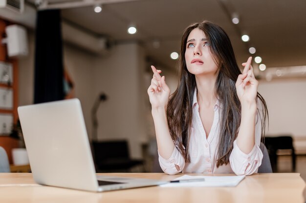 Femme espérant et tenant les doigts croisés dans le bureau