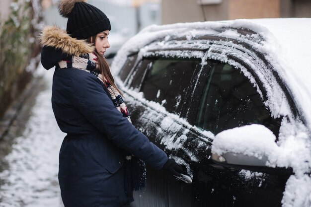 Une femme essaie d'ouvrir la voiture en cas de gel. La porte est gelée. L'hiver