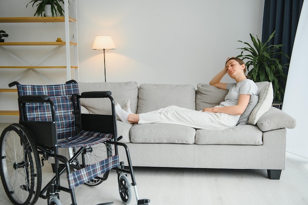 Femme essayant de s'asseoir en fauteuil roulant depuis le canapé