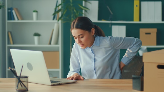 Femme essayant de se lever de la table ressentant soudainement une douleur dans le dos