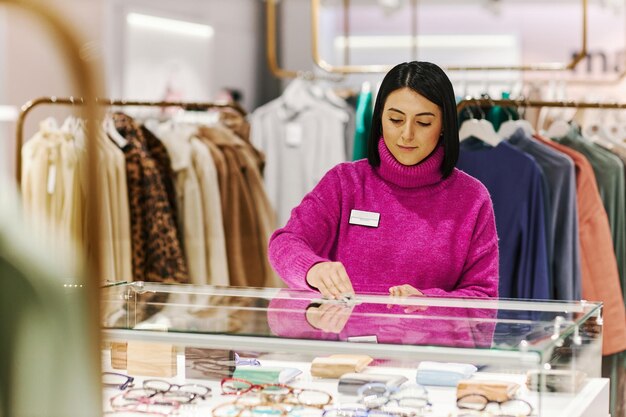 Femme essuyant un comptoir en verre dans une boutique préparant un magasin