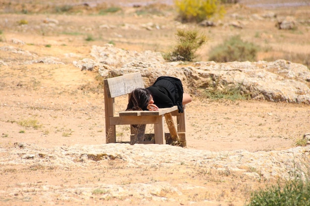 Une femme est allongée sur un banc, la tête sur la table