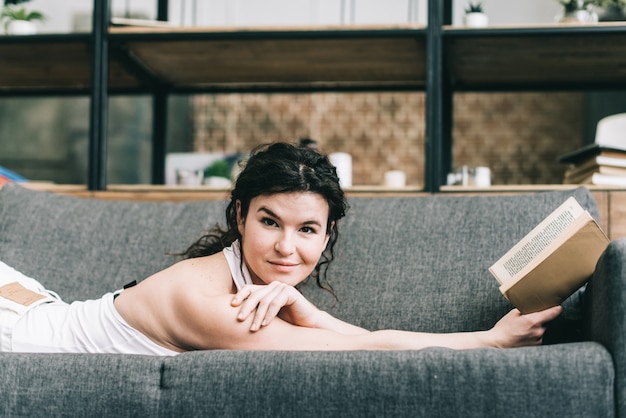 La femme est allongée sur le canapé avec un livre