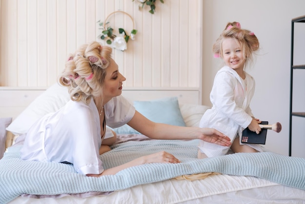 Photo une femme est allongée sur le lit avec ses cheveux en rouleaux tandis qu'une jeune fille joue