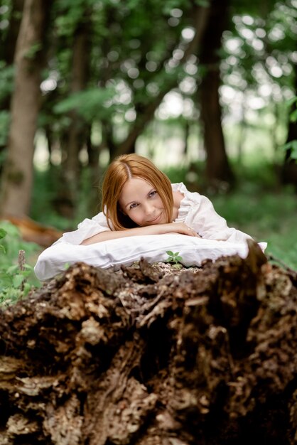 Une femme est allongée sur un oreiller sur un arbre entouré de feuillage vert