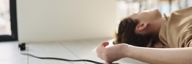 Une femme est allongée sur le sol à côté d'elle un fil d'un appareil électrique un choc en gros plan à