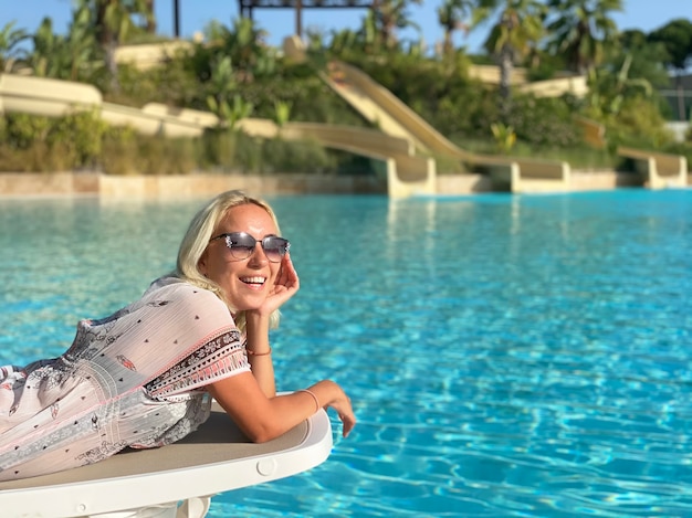 La femme est allongée sur un transat près de la piscine.