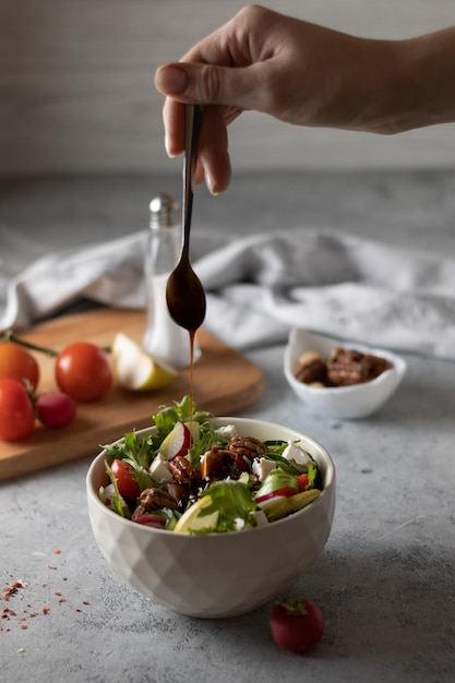 Une femme est arrosée d'huile d'olive et de vinaigrette à la sauce soja salade de poires roquette