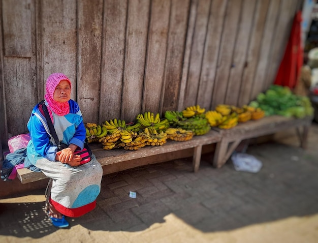 une femme est assise sur un banc avec des bananes dessus.