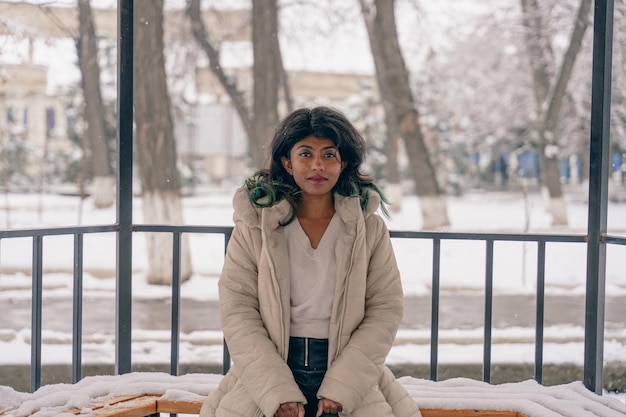 Photo une femme est assise sur un banc dans la neige